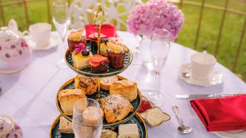 A three-tiered dessert stand with various pastries and a glass of champagne on a white tablecloth.