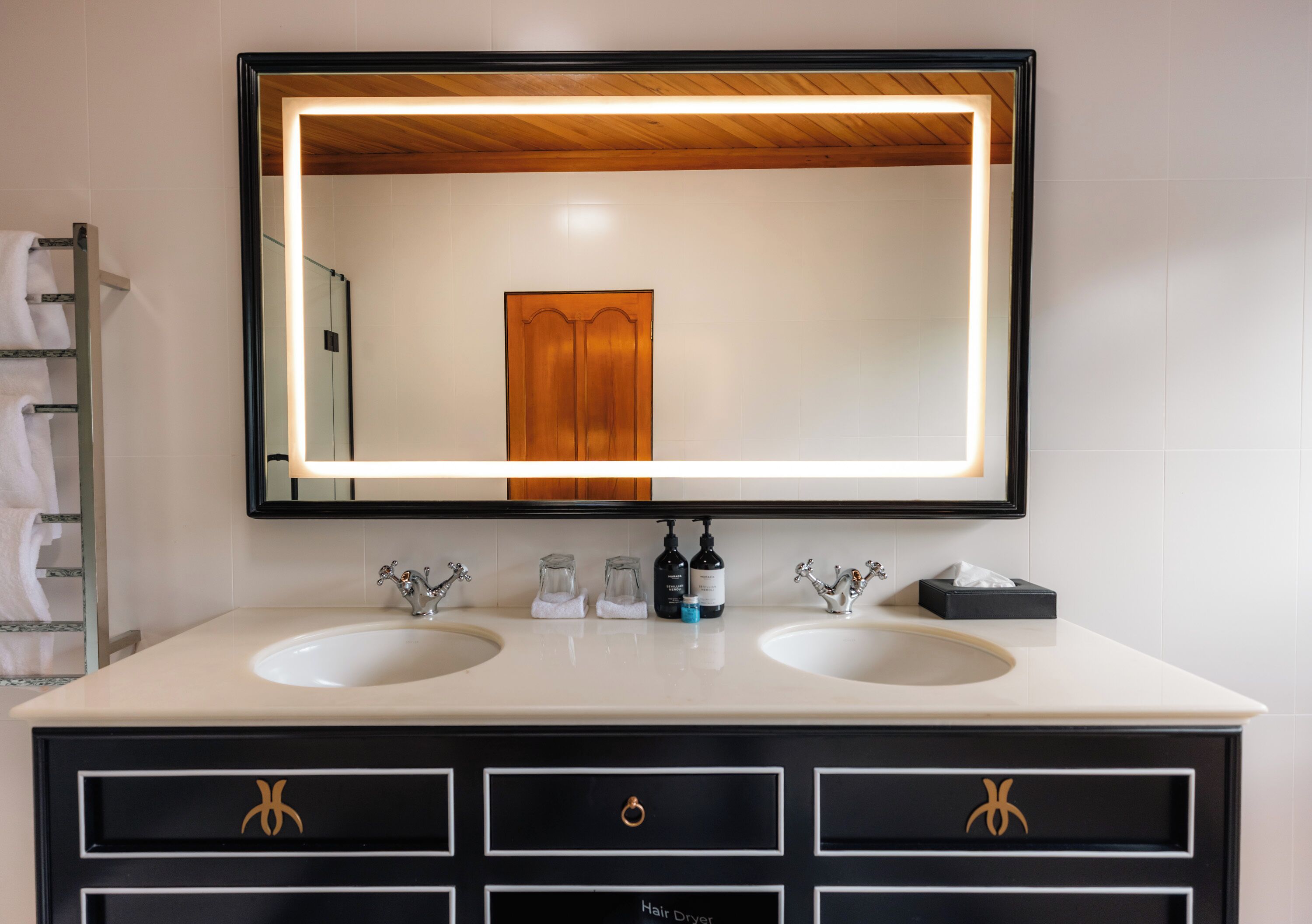 A bathroom with two sinks, a large mirror, and a hair dryer.