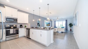 Una cocina moderna con gabinetes blancos, electrodomésticos de acero inoxidable y una isla central.