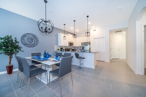 Une cuisine moderne avec des meubles blancs, un îlot central et des luminaires suspendus.