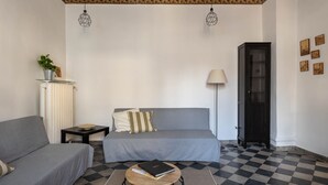 Une pièce comprenant un lit, deux canapés, une petite table, une lampe, un radiateur et un sol à carreaux.