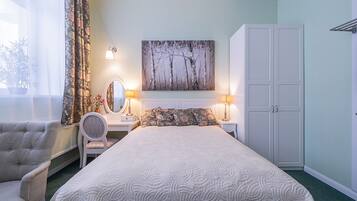 A bedroom with a bed, a chair, a dresser, a mirror, and a painting on the wall.