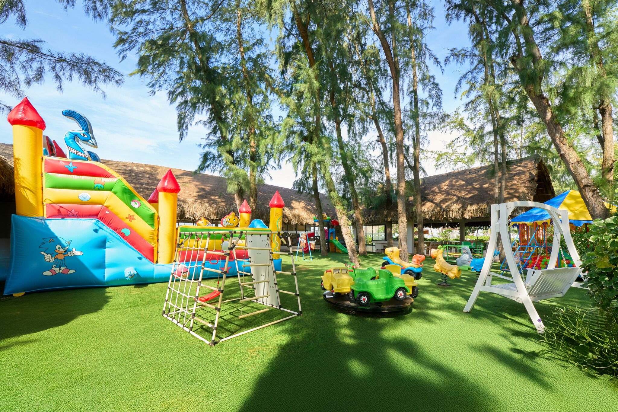 An outdoor playground with inflatable slides, a climbing structure, and toy cars.
