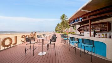 Un bar junto a la playa con terraza y vistas al océano.