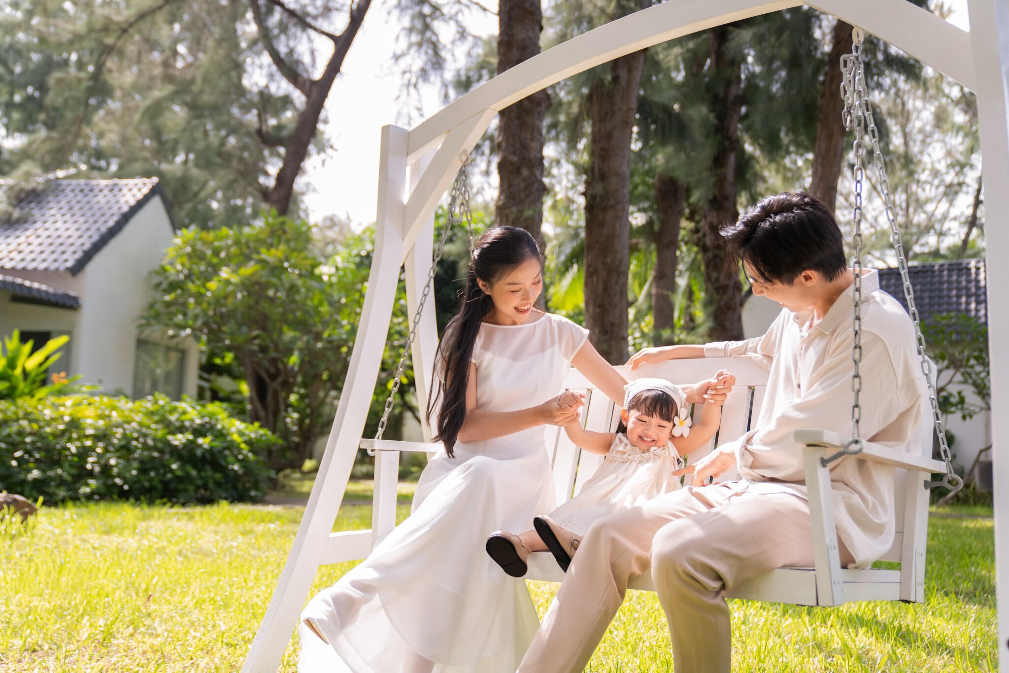 Una familia en un columpio en un jardín, con una casa al fondo.