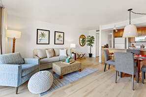 Een moderne woonkamer met een bank, fauteuils, een salontafel, en een eethoek met stoelen en een tafel.