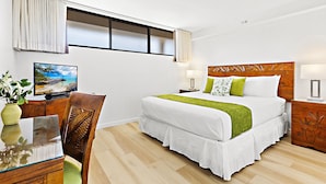 A bedroom with a bed, bedside tables, a desk with a chair, a window with curtains, and a painting on the wall. - Tropical charm, ocean touches - A guest favorite (Lahaina)