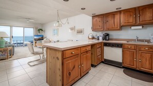A spacious kitchen with wooden cabinets, a large island, and a dishwasher. - Direct oceanfront two bedroom condo ideally located on 77th street in Ocean City (Ocean City)