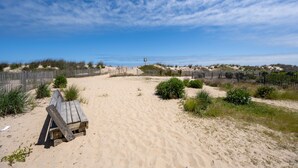 A sandy beach with a wooden bench and a fence. - Direct oceanfront two bedroom condo ideally located on 77th street in Ocean City (Ocean City)