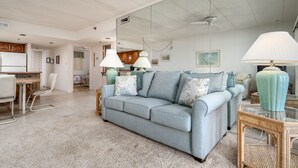 A spacious living area with a light blue sofa, a dining table, and a kitchen in the background. - Direct oceanfront two bedroom condo ideally located on 77th street in Ocean City (Ocean City)
