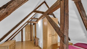 Een kamer met houten balken, een houten dressoir, een bed en een garderobe.