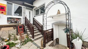 A staircase leading to a white door, a small garden with plants, and a statue of a figure.