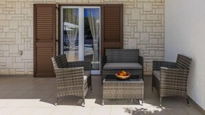 A patio with wicker furniture, a glass door, and a stone wall. - Vacation home Reaa by Interhome (Barban)