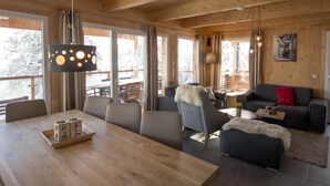 Un intérieur en bois comprenant une table à manger, des chaises, un canapé et un luminaire suspendu.