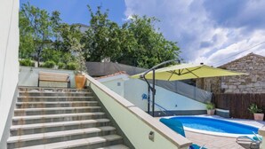 En bostadsfastighet med en swimmingpool, en trappa som leder till ett överbyggt område och en stenmur.
