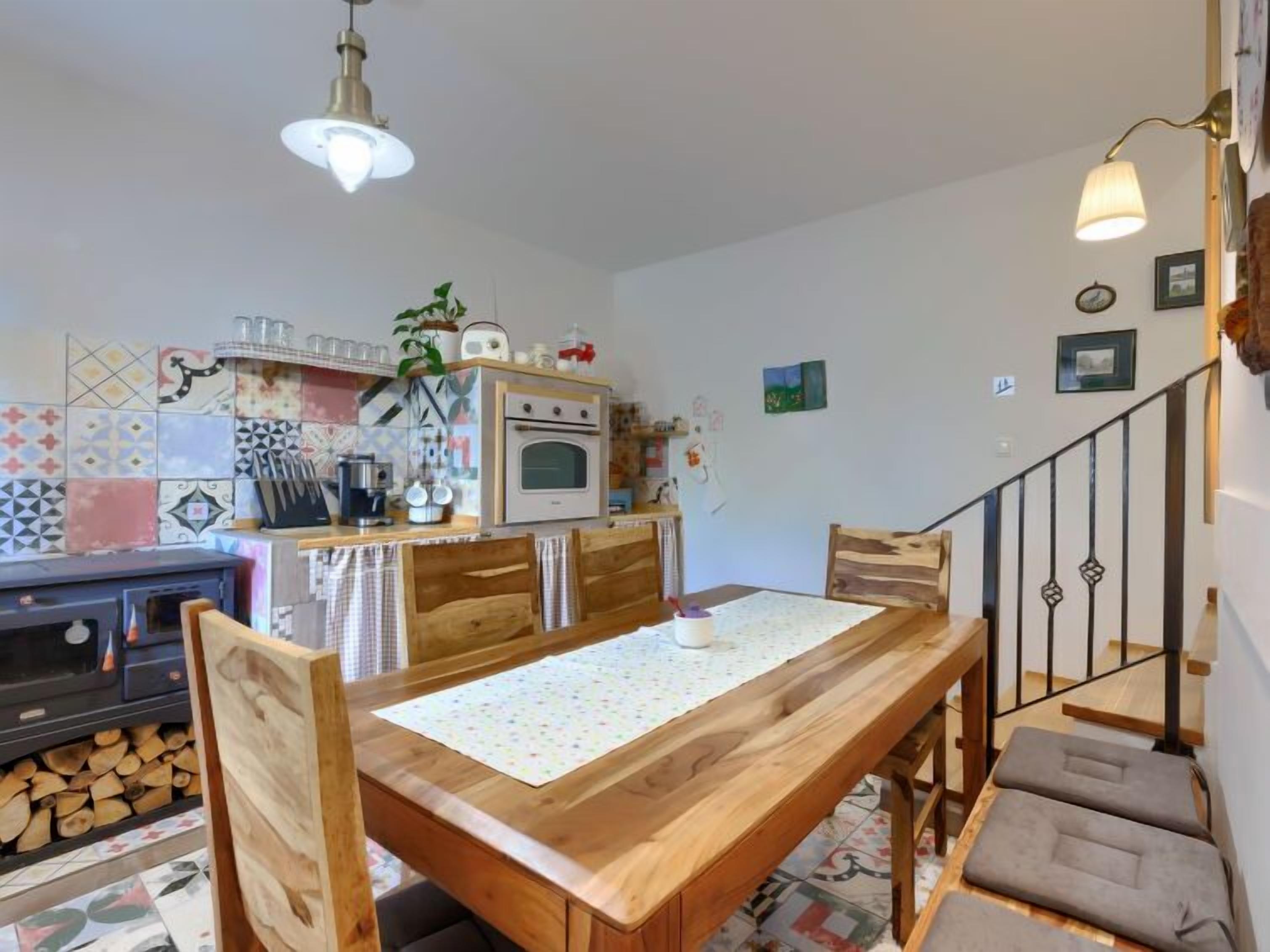 A dining area with a wooden table, chairs, and a kitchen in the background.