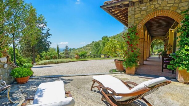 A stone building with a covered patio area, two lounge chairs, and potted plants. - Il Farinaio by Interhome (Cortona)