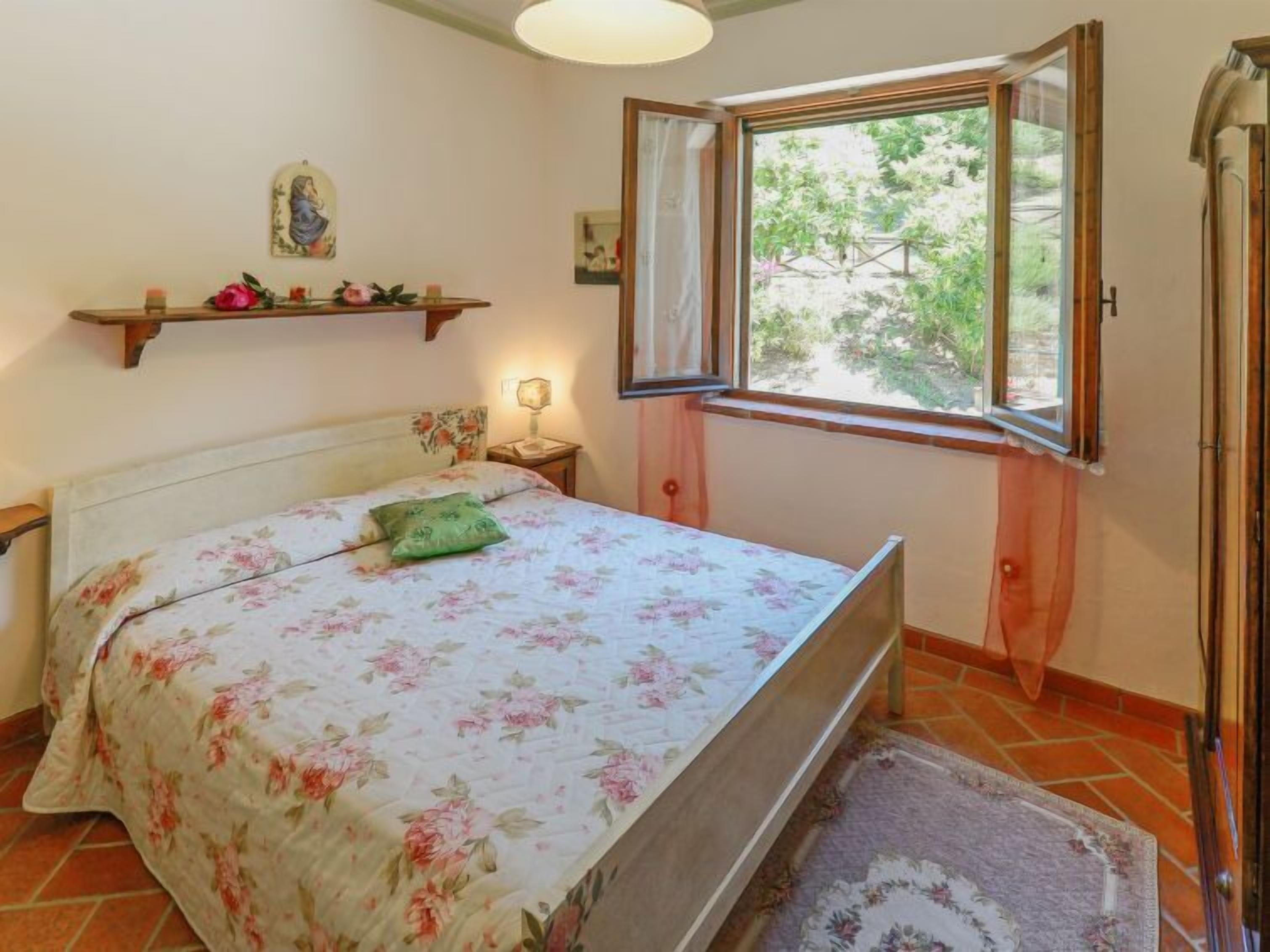 Une chambre à coucher comprenant un lit, une fenêtre, une table de chevet et une étagère murale décorative.