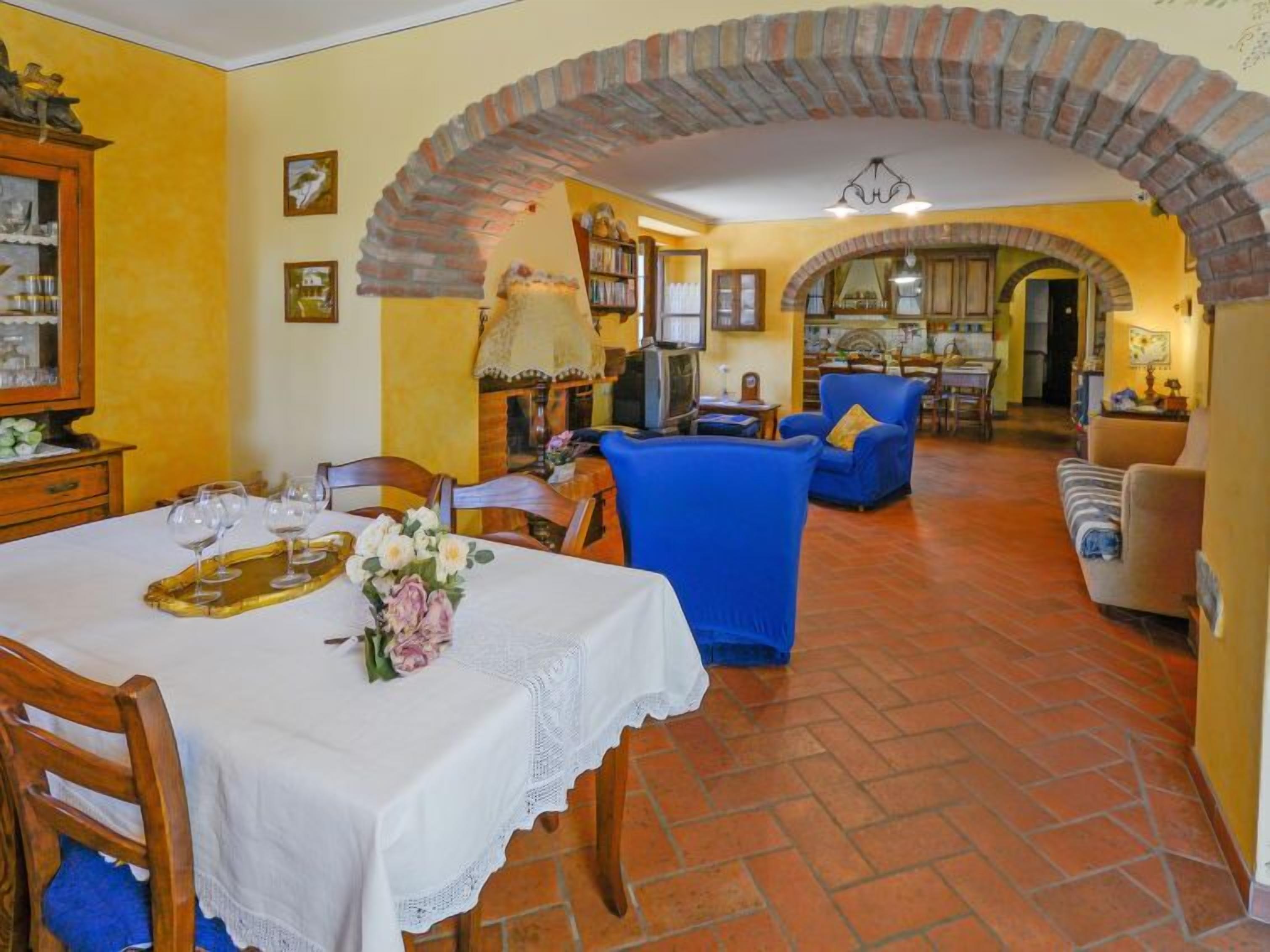 Un coin repas avec une table mise pour le repas, un fauteuil bleu et un canapé.