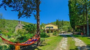 A house with a stone pathway leading to a pool, surrounded by lush greenery and a hammock. - Il Farinaio by Interhome (Cortona)
