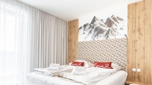 Una habitación de hotel con una cama grande, cabecero de madera y un mural de montañas en la pared.