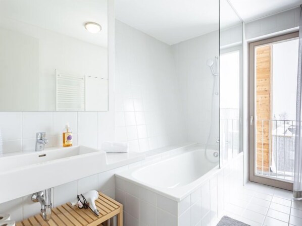 Un baño moderno con un espejo grande, dos lavamanos, una bañera y una ducha.