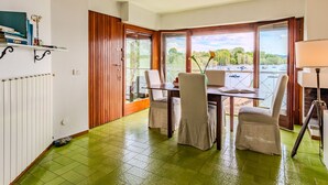 A dining area with a table and chairs, a view of boats on water, and a green tiled floor.