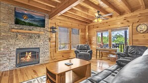 A cozy cabin interior with a stone fireplace, leather furniture, and a television displaying 'BeanCamp'. - A Bliss - game room, pool access, hot tub and more (Sevierville)