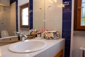 Un baño con un lavamanos blanco, un espejo y una ventana.