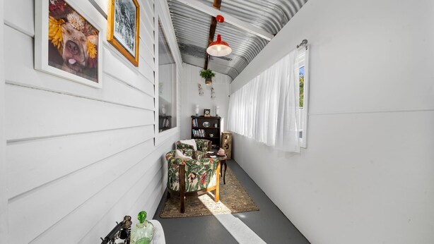 A narrow hallway with white walls, a wooden floor, a small table with chairs, a bookshelf, and a hanging plant. - Olive Nook in Katoomba (Katoomba)