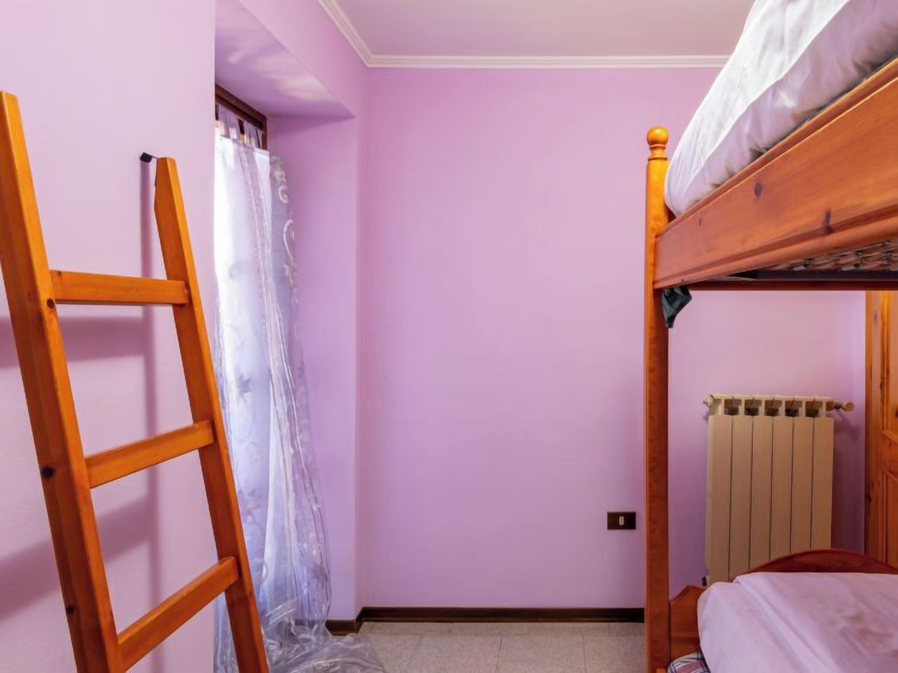 A small room with a bunk bed, a wooden ladder, and a radiator.