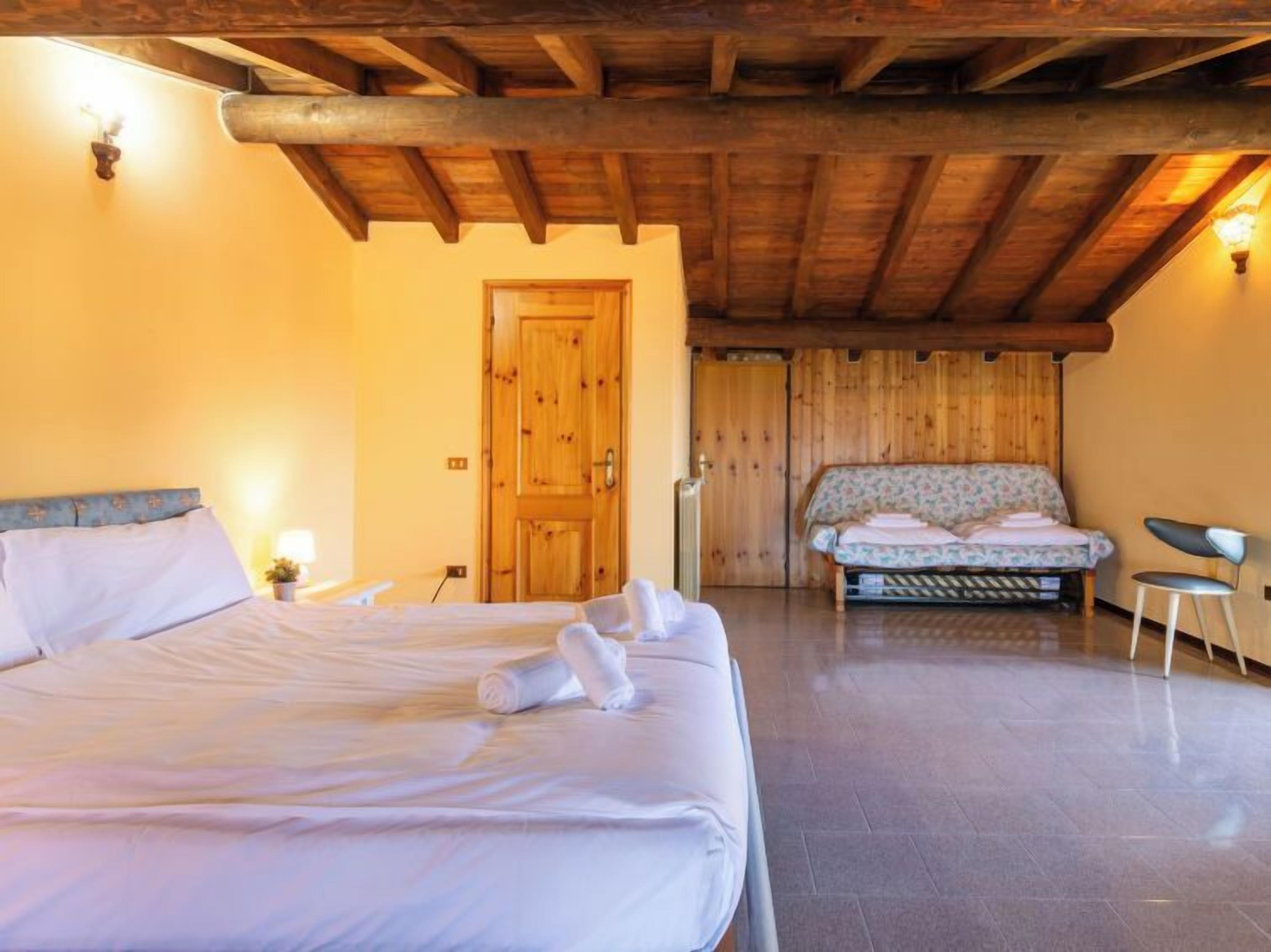 Une chambre à coucher avec un grand lit, un petit canapé, une chaise et une porte en bois.