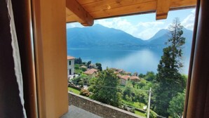 Una habitación con techo de madera y un ventanal grande con vistas a un lago y montañas.