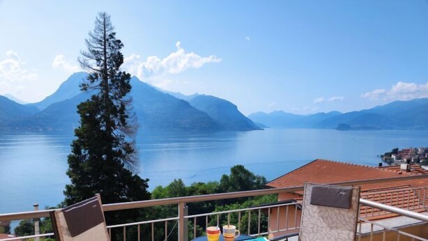 Un balcón con una mesa para dos, con vistas a un lago y montañas.