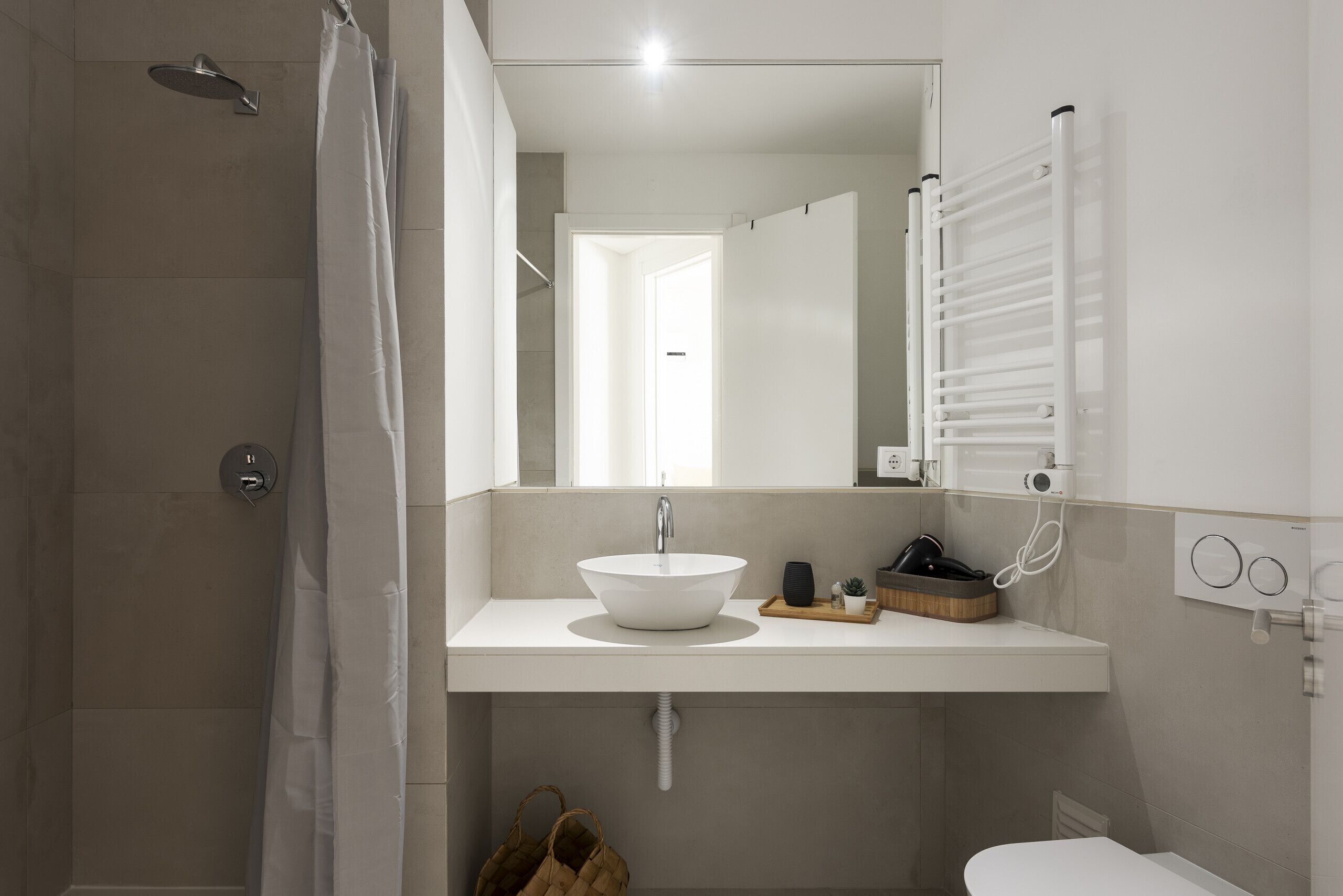 A modern bathroom with a shower, a sink with a mirror, and a toilet.
