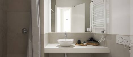 A modern bathroom with a shower, a sink with a mirror, and a toilet.