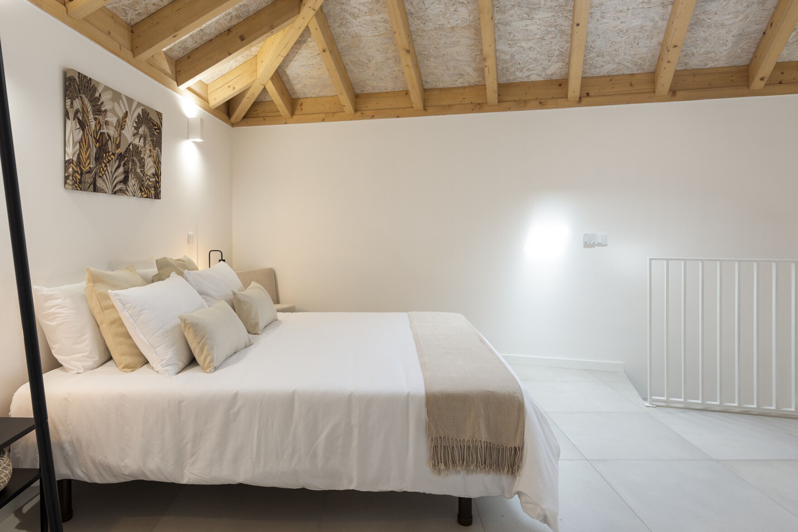 Une chambre avec un plafond en bois, un lit avec une literie blanche et un radiateur blanc.