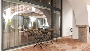 Een terras met een glazen wand, een tafel met stoelen en een stenen pilaar.