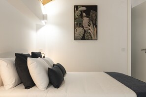 A bedroom with a bed, pillows, and a wall-mounted artwork.