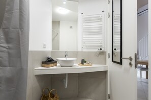 A modern bathroom with a white sink, a mirror, and a towel rack.