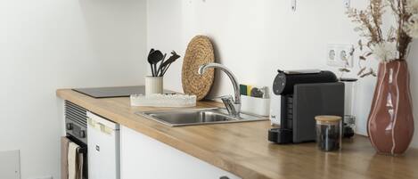Una cocina moderna con encimera de madera, pileta de acero inoxidable y horno empotrado.