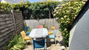 Eine Terrasse mit Tisch und Stühlen, umgeben von einem Holzzaun und Pflanzen.