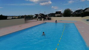 Ein Schwimmbad mit klarem, blauem Wasser, gelben Fahrbahnen und einigen darin schwimmenden Personen.