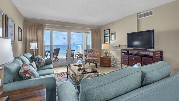 A spacious living room with a large TV, comfortable seating, and a balcony with a view of the ocean. - Sandy Key 524:  2 BR / 2 BA Gulf Front Condo in Perdido Key, FL  Sleeps 6 (Pensacola)