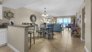 A spacious living area with a dining table and chairs, a sofa, and a view of the ocean. - Sandy Key 524:  2 BR / 2 BA Gulf Front Condo in Perdido Key, FL  Sleeps 6 (Pensacola)