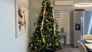Un salon moderne avec un sapin de Noël décoré, un coin repas et une cuisine.