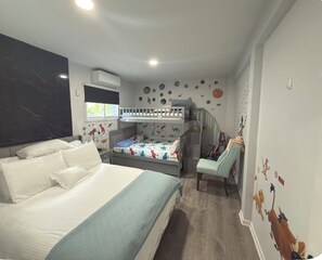 A child's bedroom with a bunk bed, a desk, and a chair.