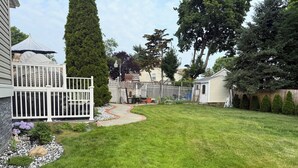 Un jardin bien entretenu, avec un chemin pavé, une clôture blanche et une variété d’arbres et d’arbustes.