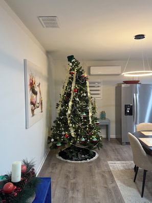 A kitchen with a Christmas tree, a dining table, and a refrigerator.