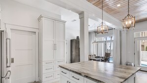 Una cocina moderna con armarios blancos, encimera de granito e iluminación colgante.